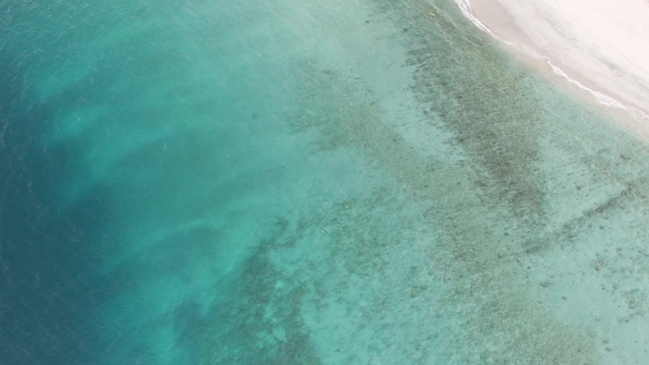 Clear shallow water reveals seabed patterns below an upper-edge white sand beach in Los Barriles, with no visible people.