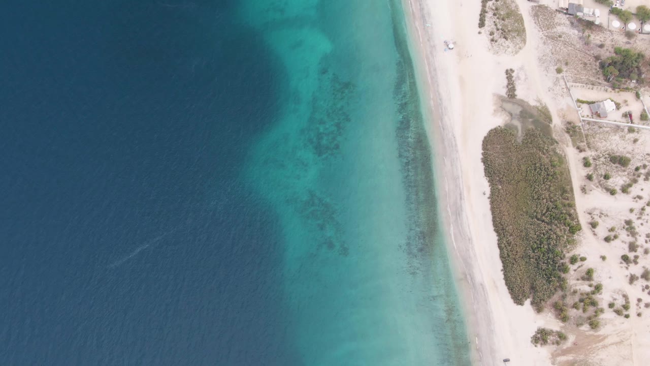 Overhead coastal road and ocean with vehicle near the lower beach edge