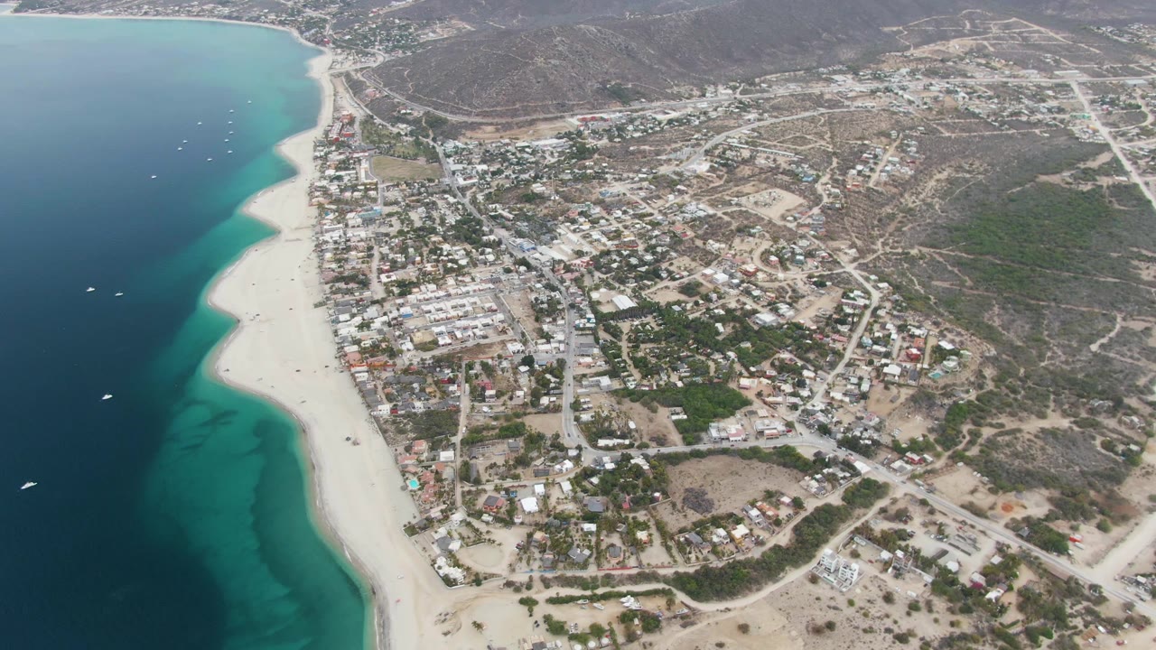 Third frame shows Los Barriles from above with offshore boats in blue water, a bright sand strip, town streets and buildings, scrubby hills, and no visible people.