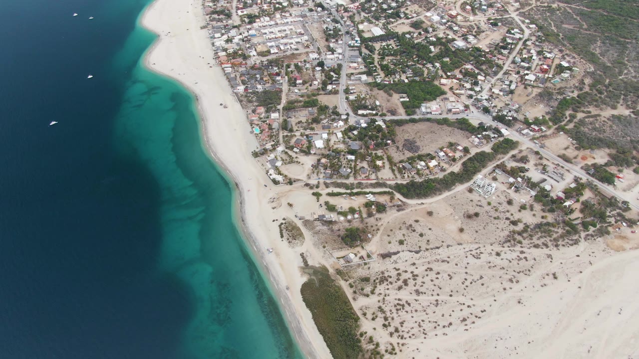 Overhead beach view with turquoise shallows and town inland.