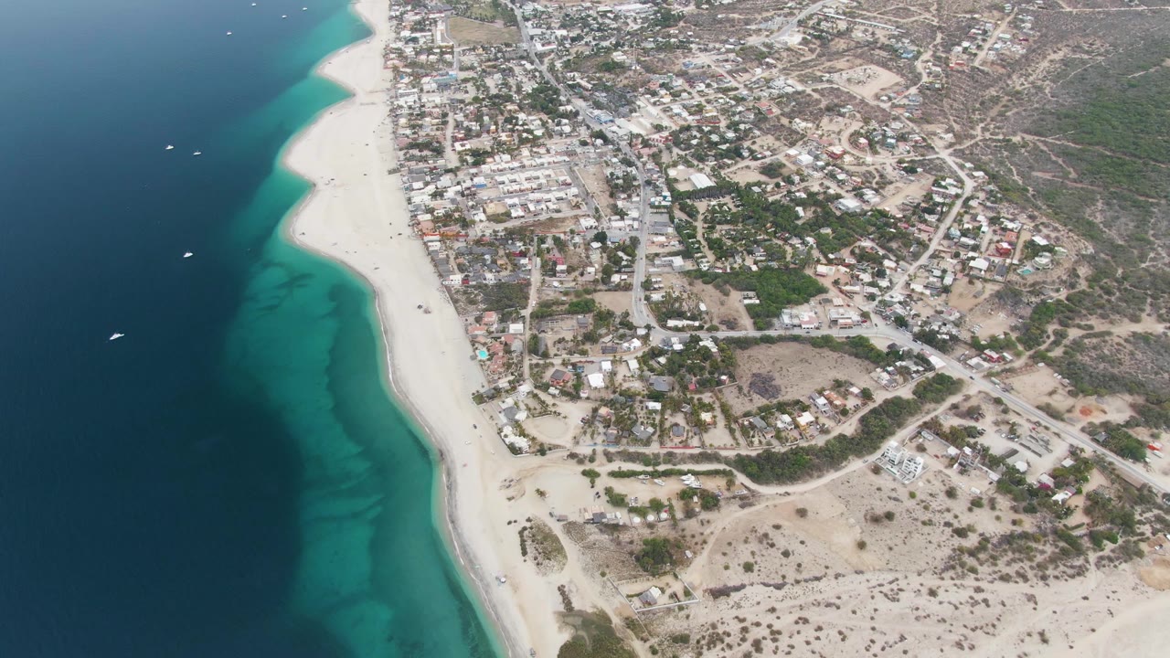 Coastline aerial with ocean on the left and town on the right.