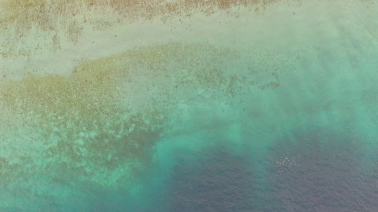 Overhead Los Barriles, Mexico view with brown and pale seabed markings under turquoise water, darker ocean across the lower portion, and no visible people.
