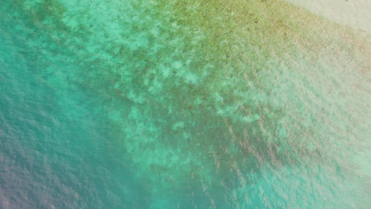 Turquoise shallow ocean water with sandy bottom and ripples