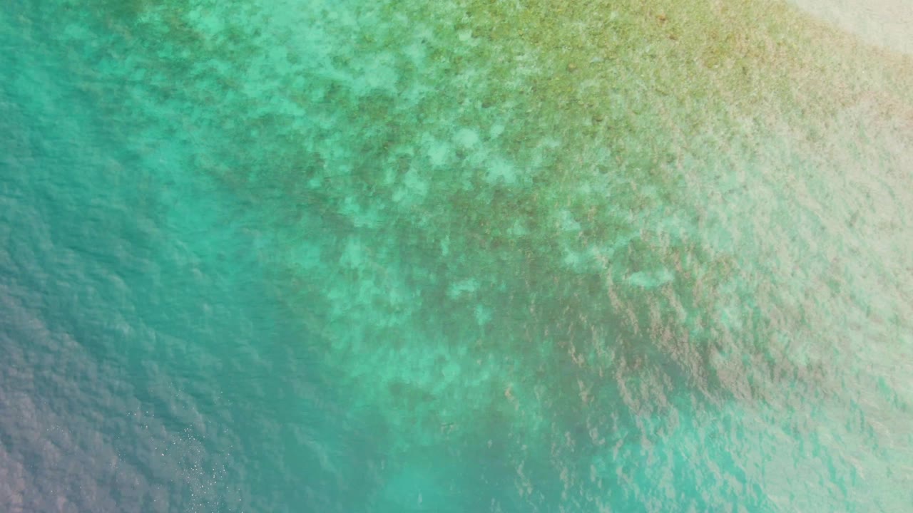 Clear green-blue water fills the frame in Los Barriles, Mexico, with soft ripples crossing a pale shallow bottom and no visible people.
