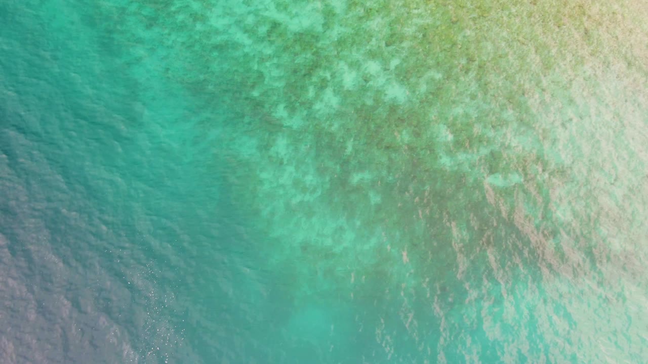 Shallow turquoise sea in Los Barriles, Mexico, with a pale sandy bottom visible under gentle ripples and no visible people.