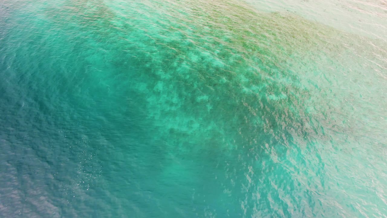 Aerial-looking frame of clear teal and turquoise water in Los Barriles, Baja California Sur, with pale reef-like patches spread across the center and no visible people.
