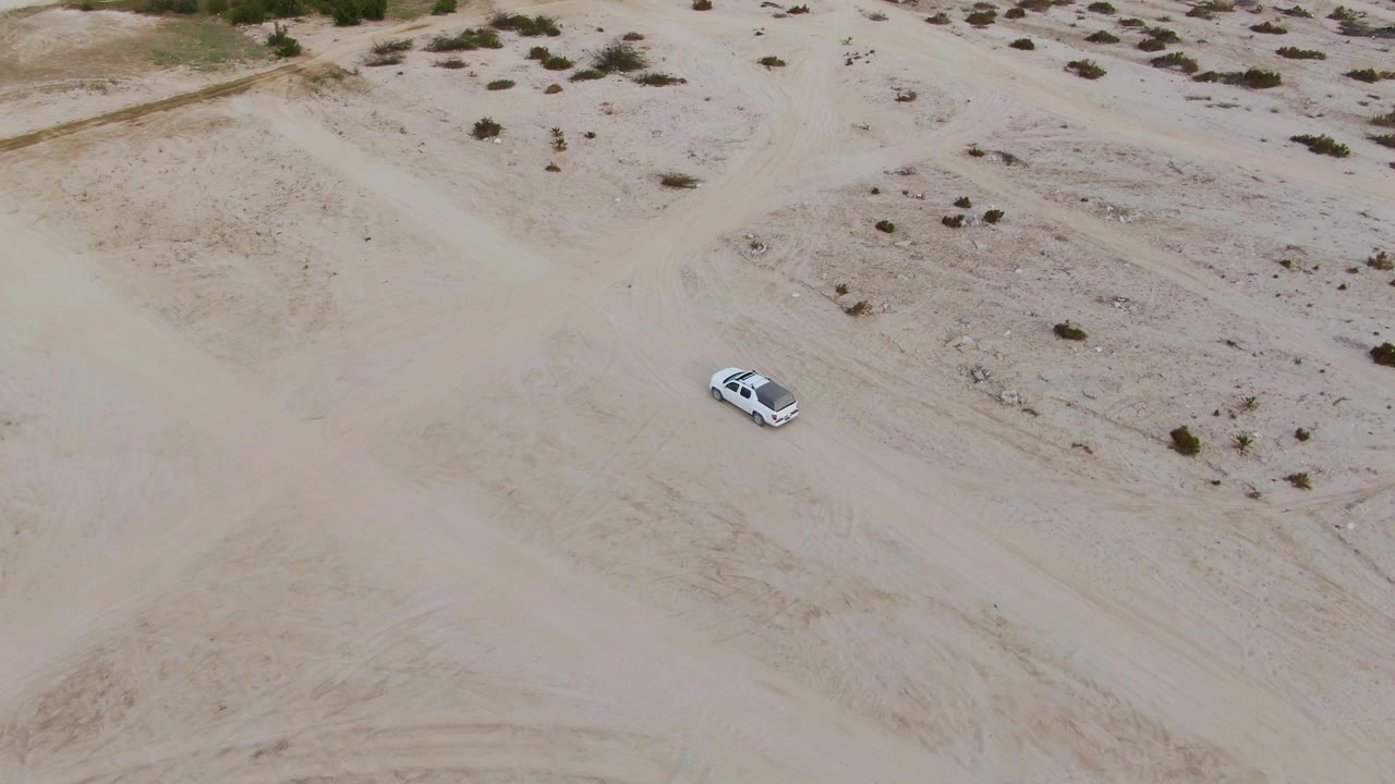 White car driving across sandy inland dunes