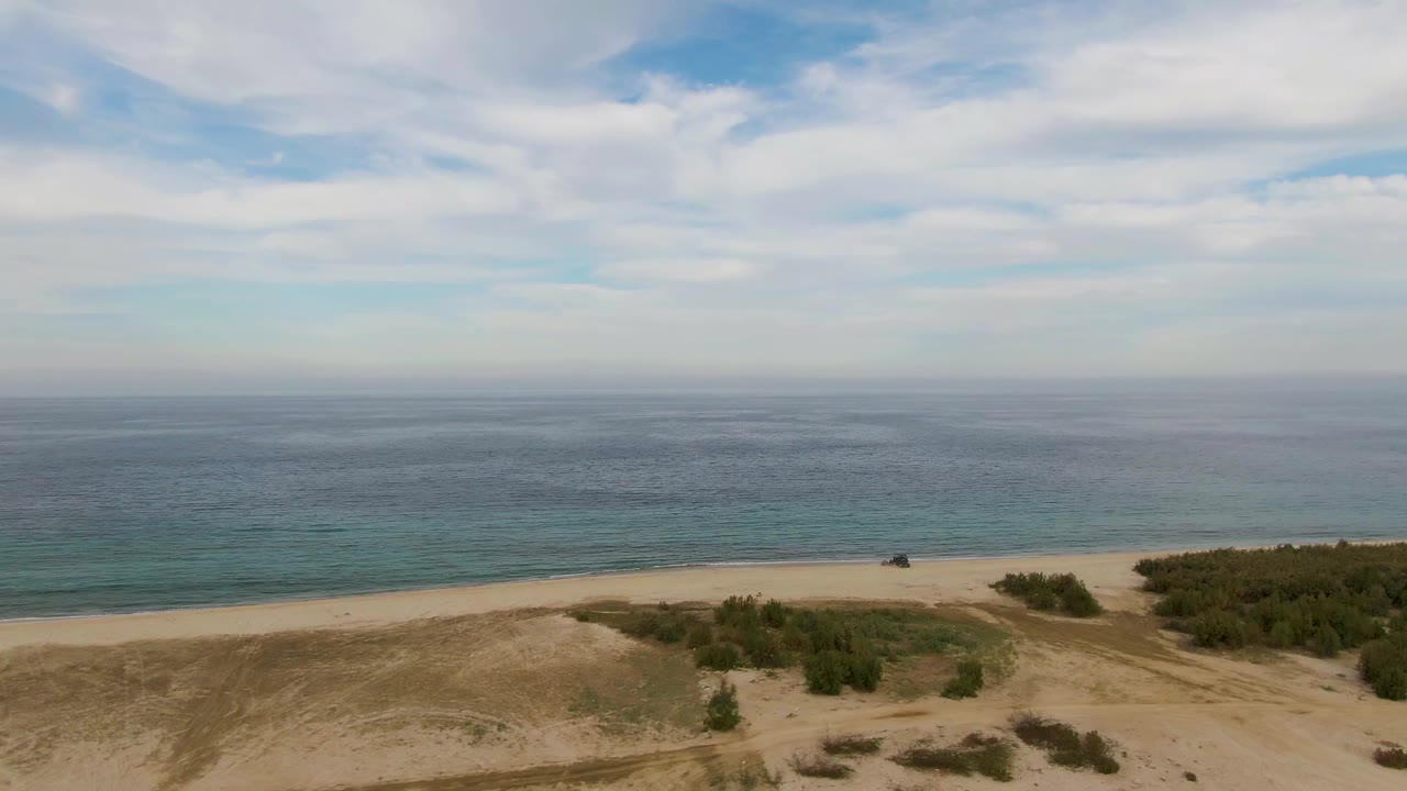 Aerial frame over sandy dunes and low vegetation near the ocean in Los Barriles, Baja California Sur, with no visible people.