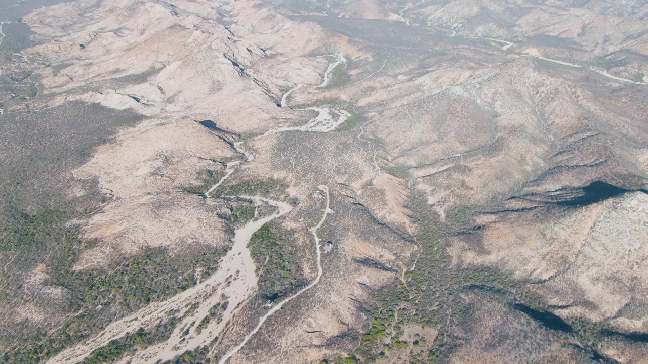 Dry river channel and scrub-covered ridges seen from above.
