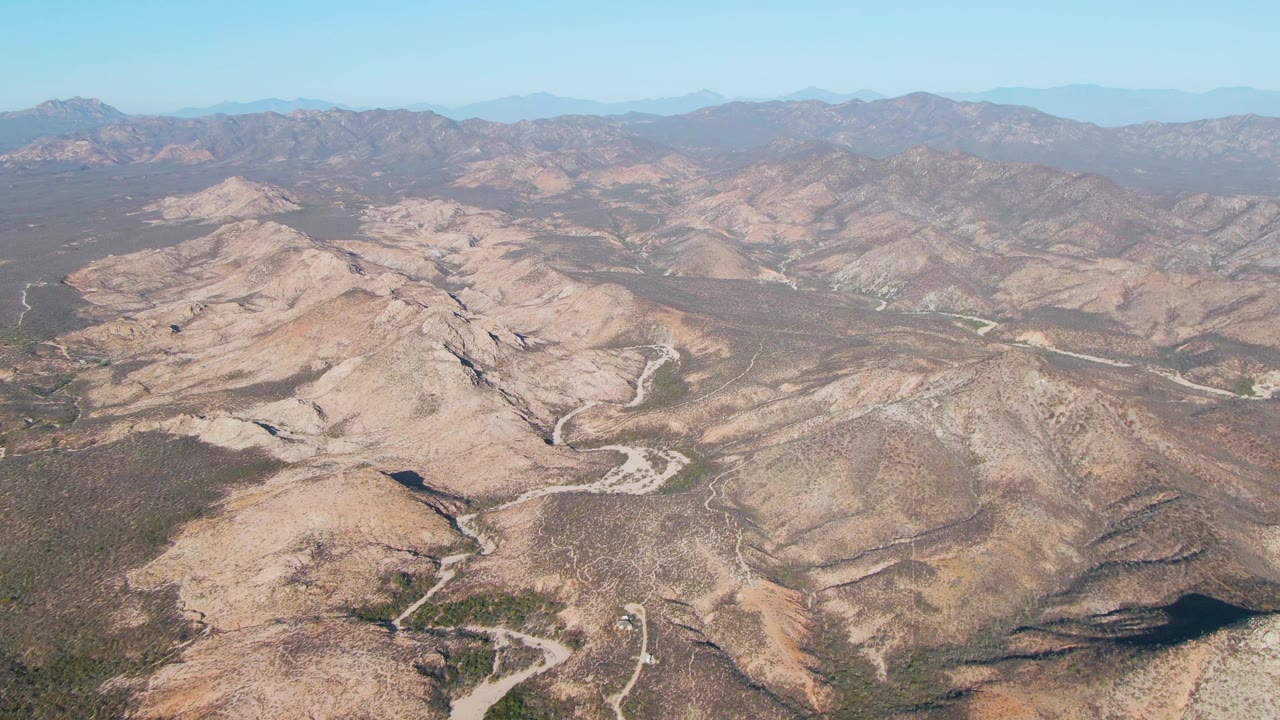 Aerial view of winding roads through dry rocky mountains.