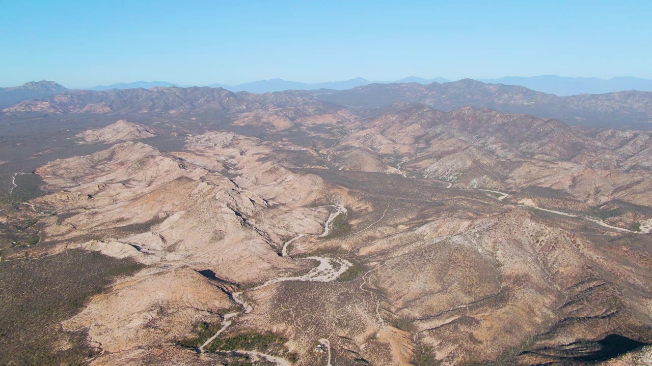 Dry ridgelines with pale roads curving through arid valleys.