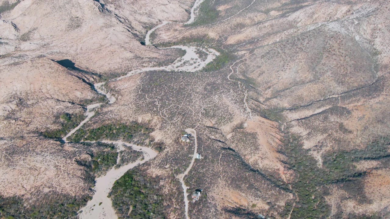 Aerial view of vehicles on a winding dirt road in dry hills