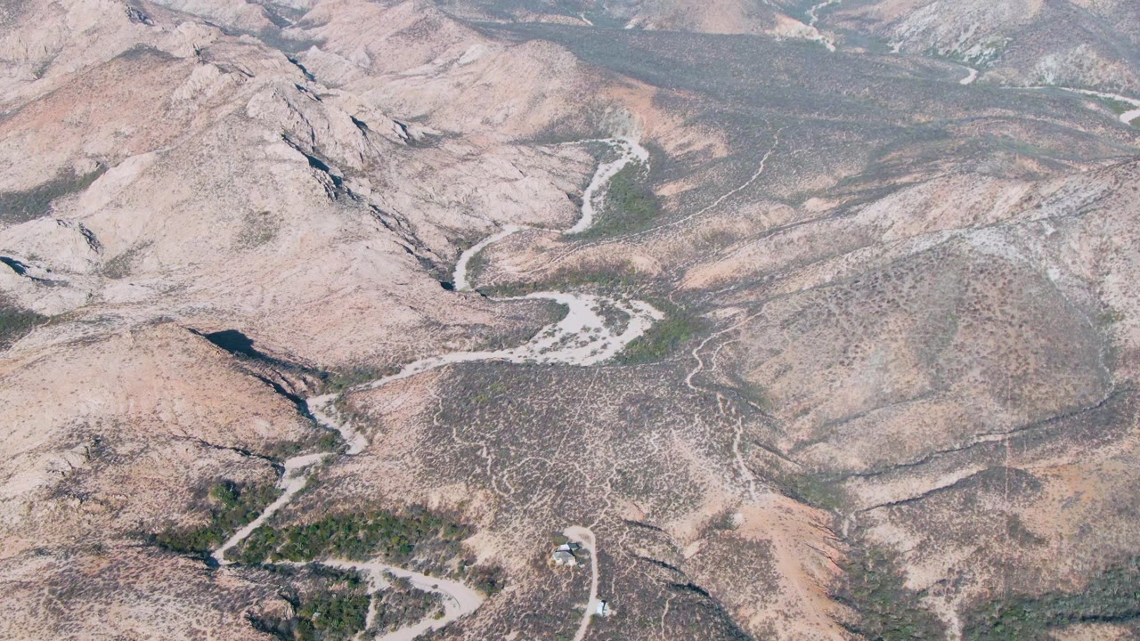 Rocky desert-like hills crossed by pale winding roads and dry washes.