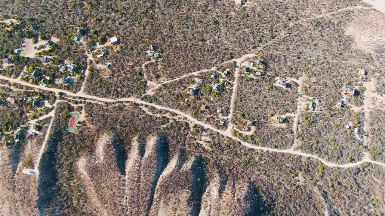 Drone view of winding roads crossing a dry rural settlement.