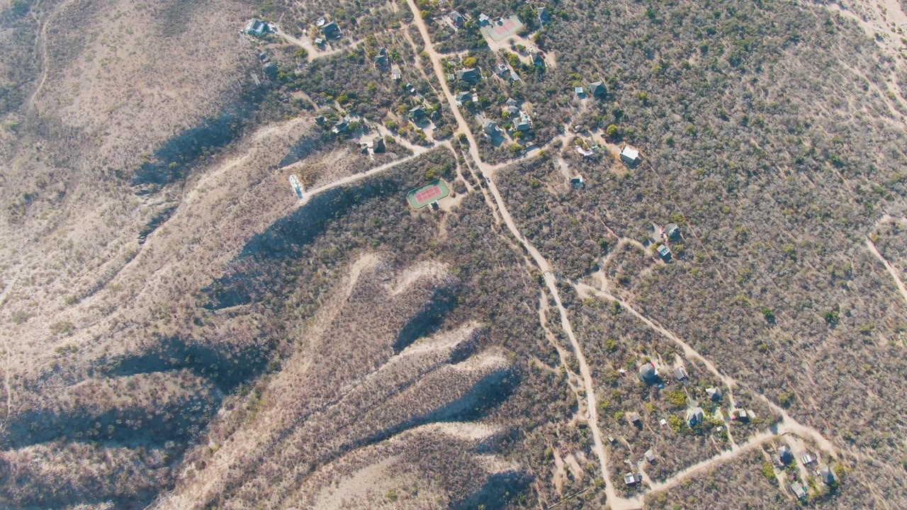 Aerial dry landscape with roads, homes, and shadowed ridges