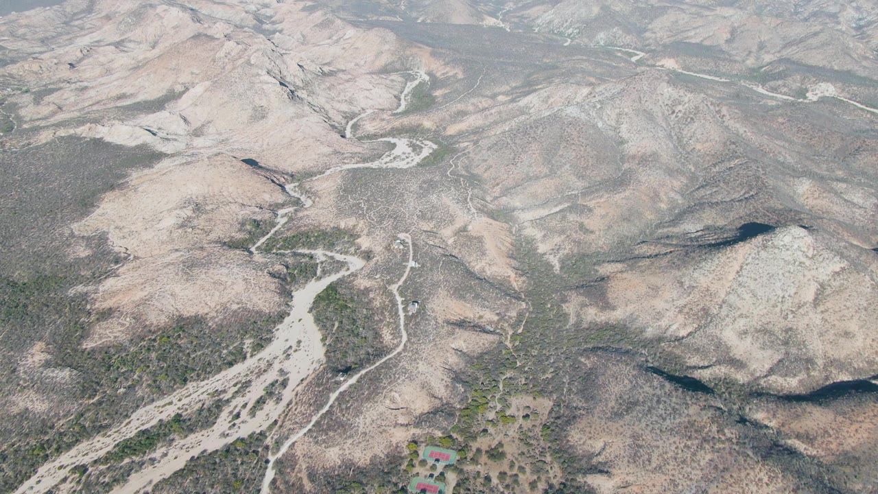 Dry mountain terrain with a pale road curving across scrubland