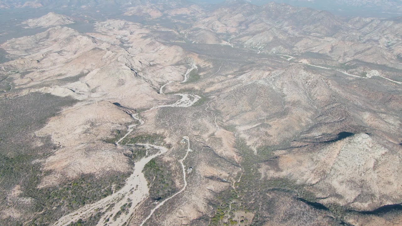 Aerial view of a dry riverbed winding through arid rocky hills.