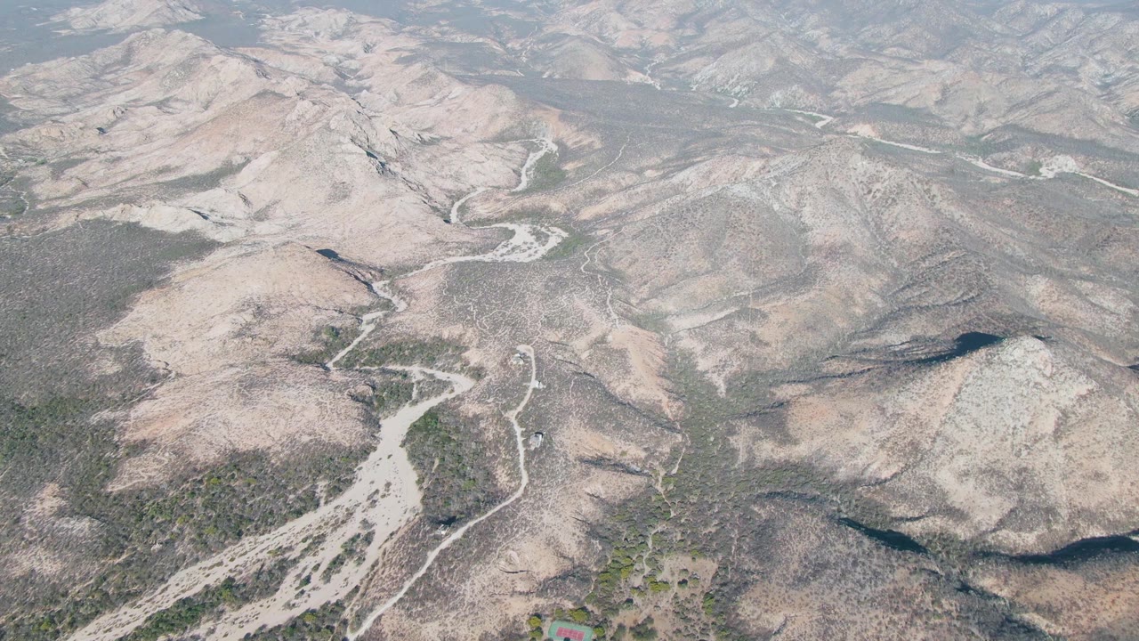 Arid hillside with dirt road, rocky ridges, and sparse scrub.