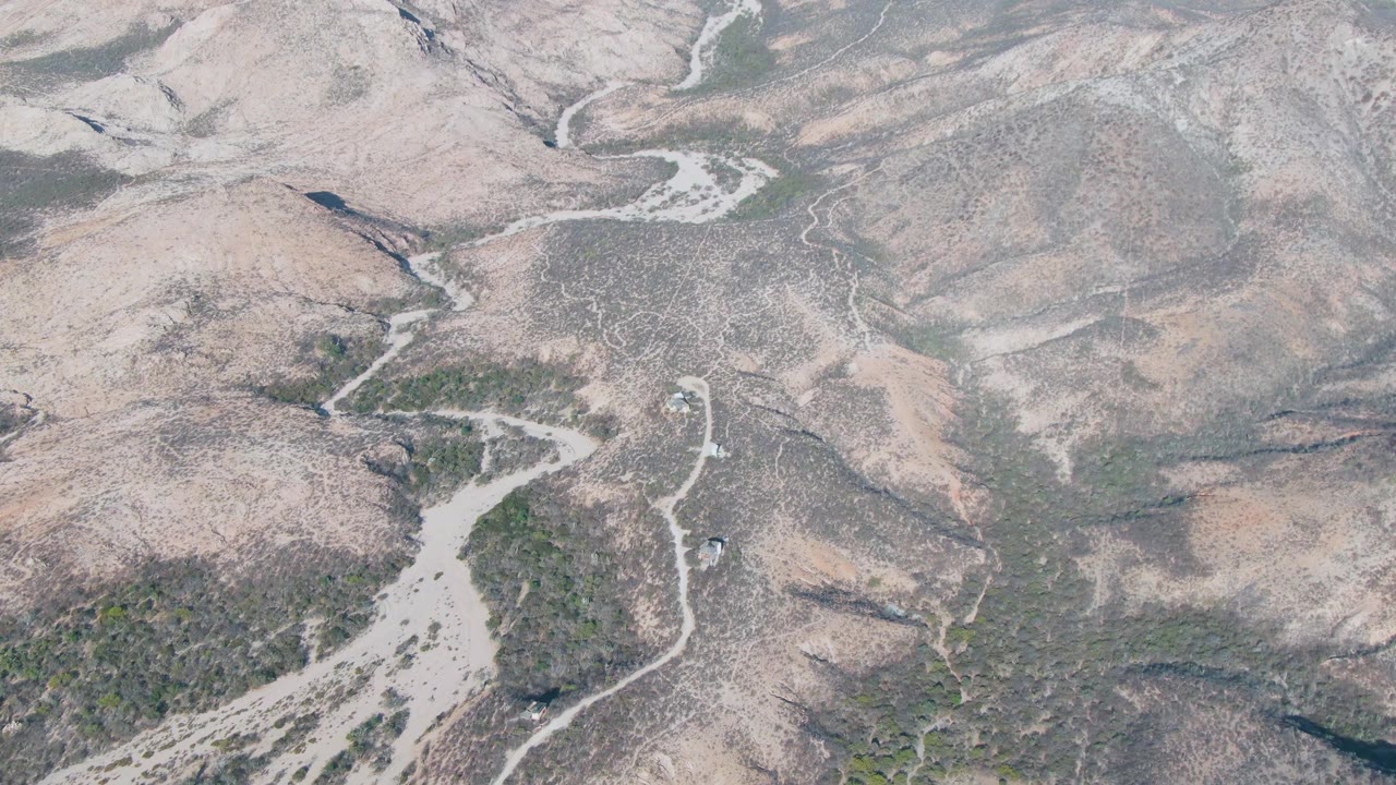 Aerial view of a pale winding riverbed through dry hills