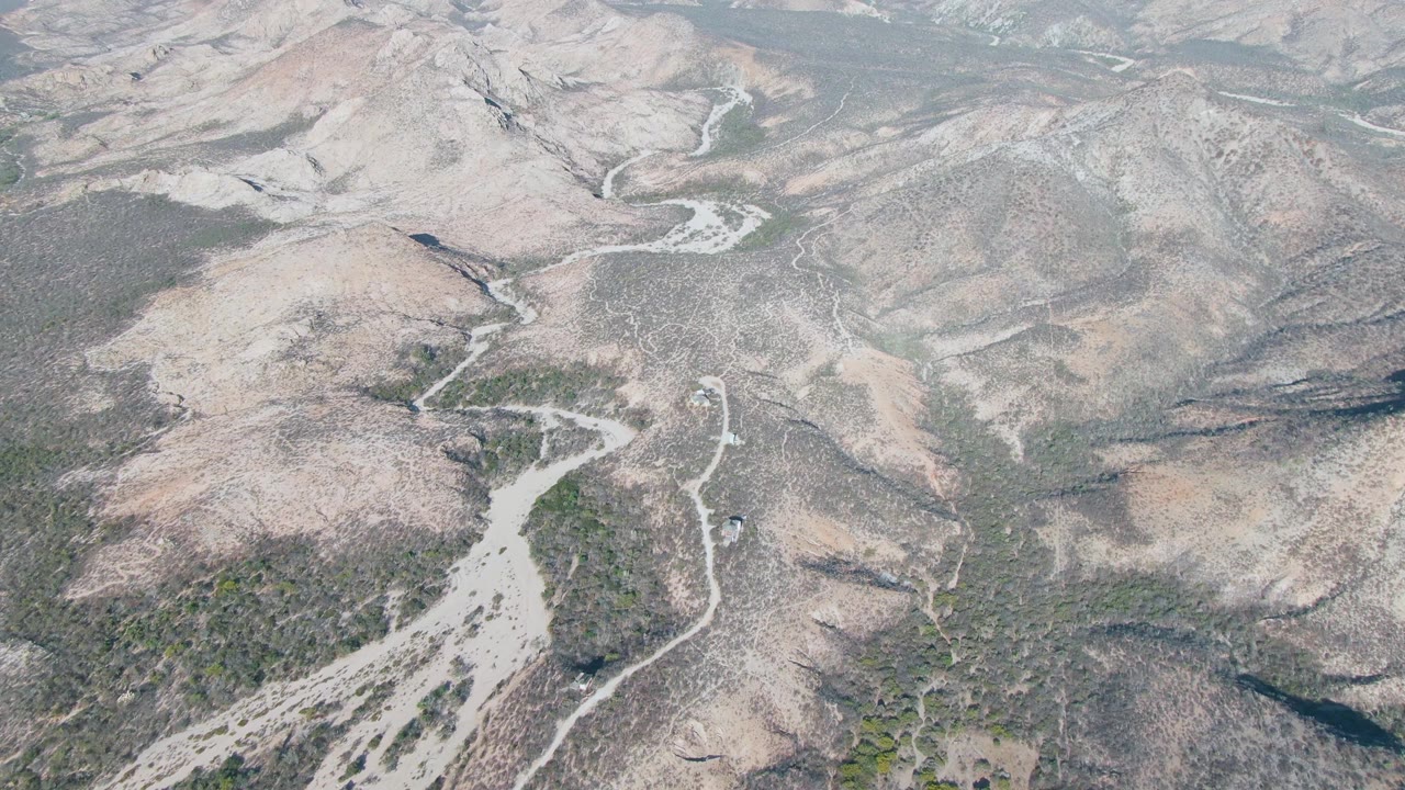 Aerial view of a winding pale river channel through rocky hills