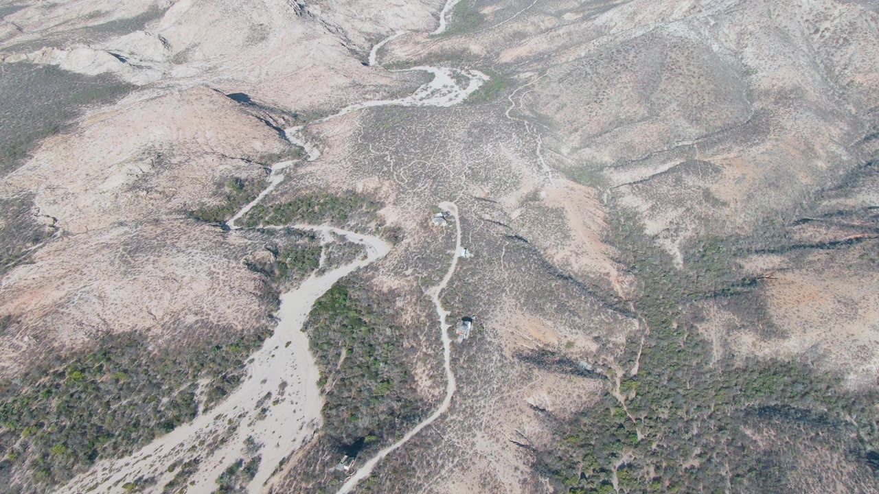 Small vehicle on a winding dirt road in arid hills.