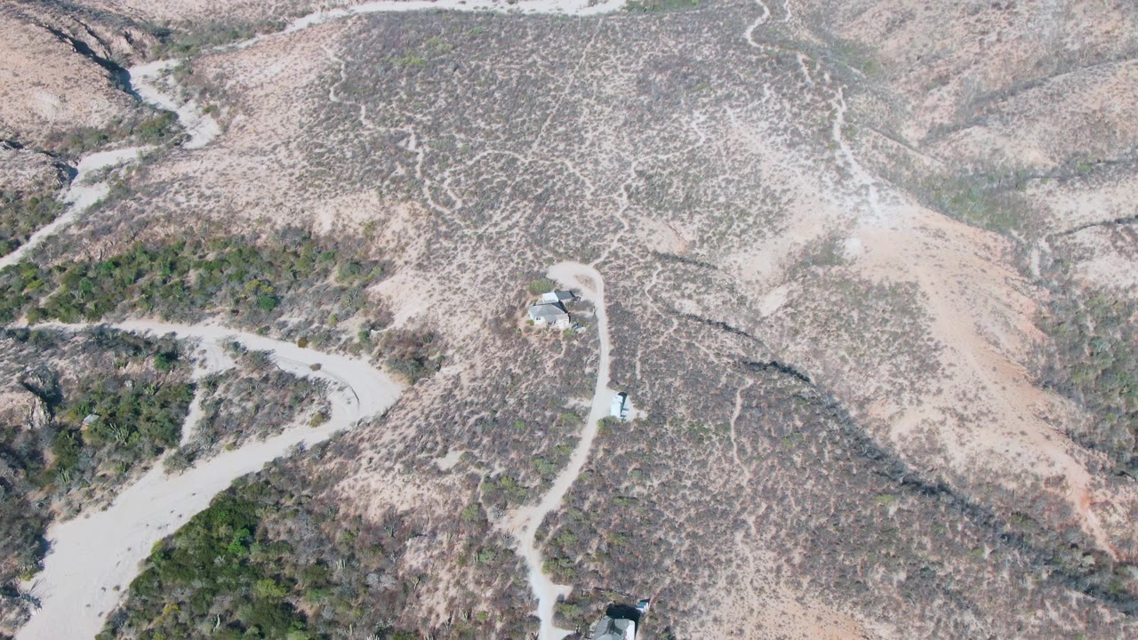 Drone view of dirt roads curving through scrub-covered hills