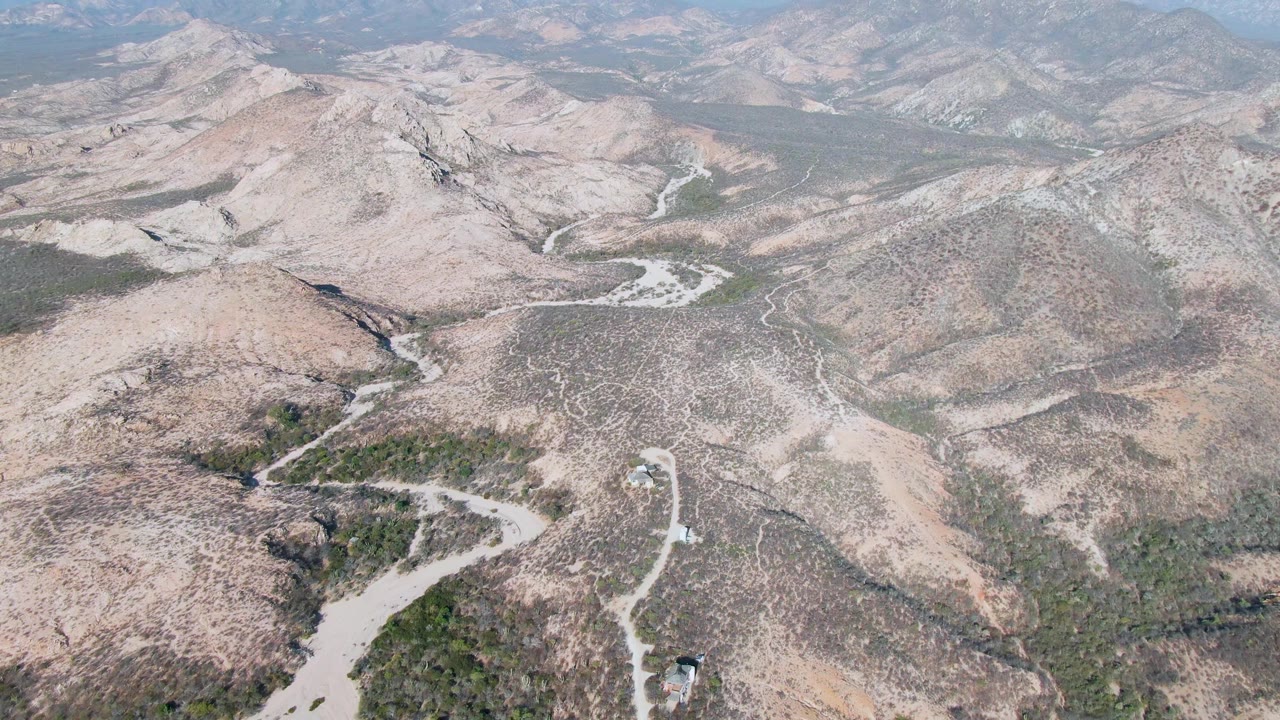 Aerial landscape of dry hills and a winding road through scrub