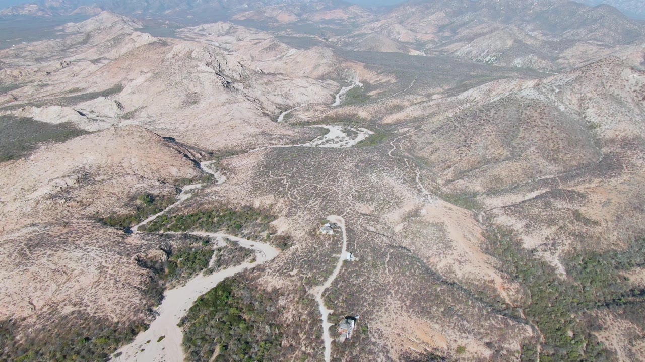 Aerial view of an empty dirt road in dry mountain terrain.