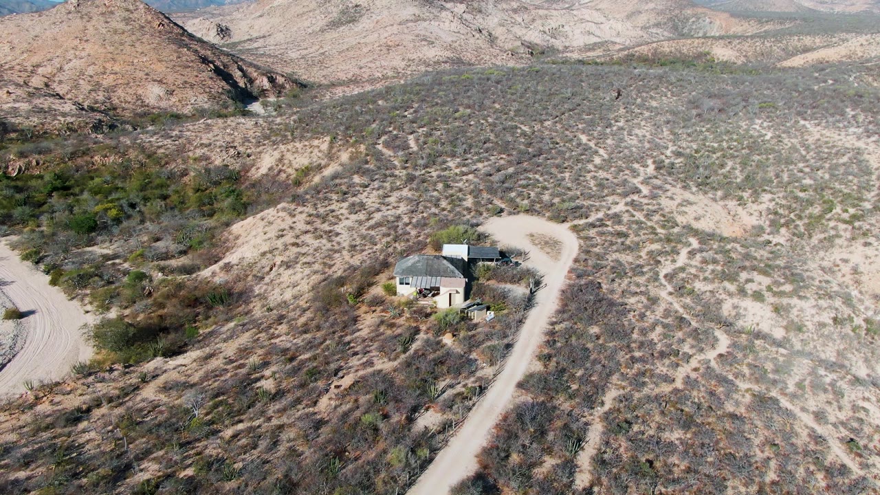 Small desert building and pale road seen from above.