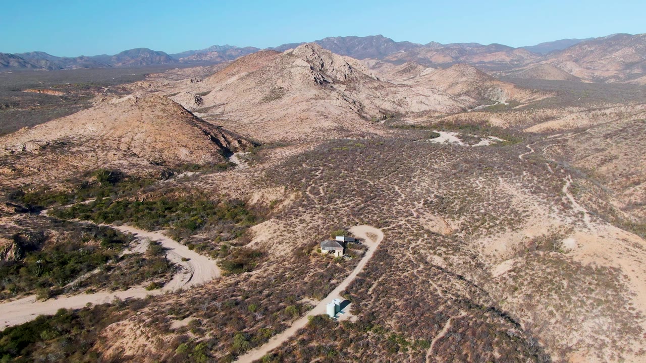Aerial view of a vehicle on a winding dirt road in arid hills