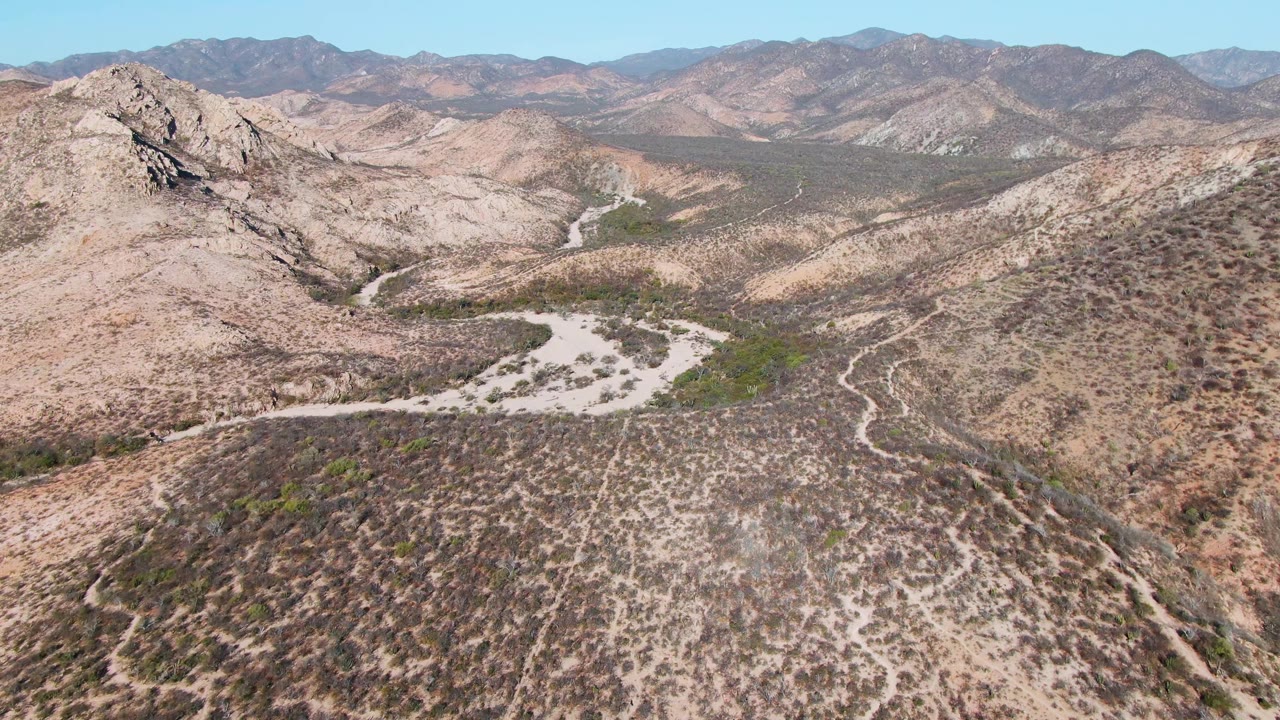 Rocky desert ridge in the foreground with winding tracks and mountains beyond.