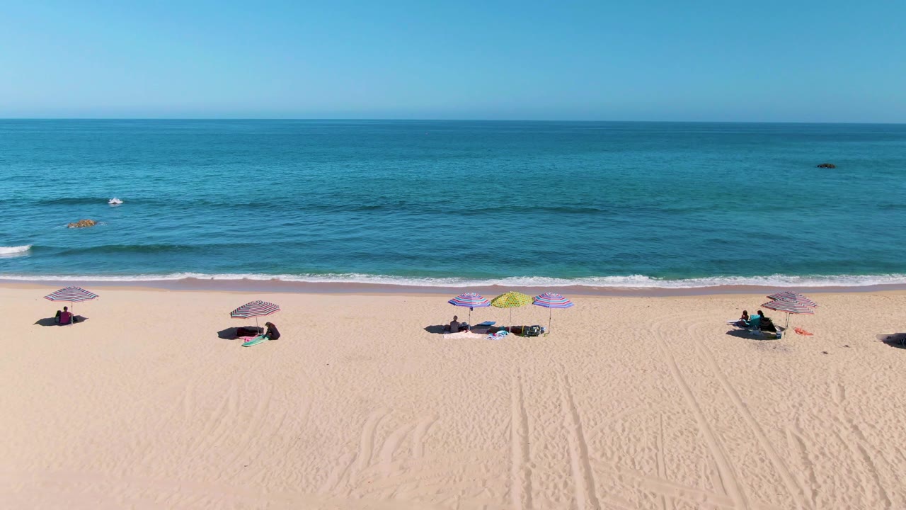 Colorful umbrellas on a sandy beach with turquoise water behind them.