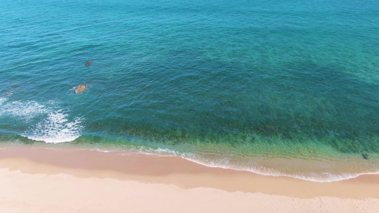 Mostly ocean and sand with small breaking wave