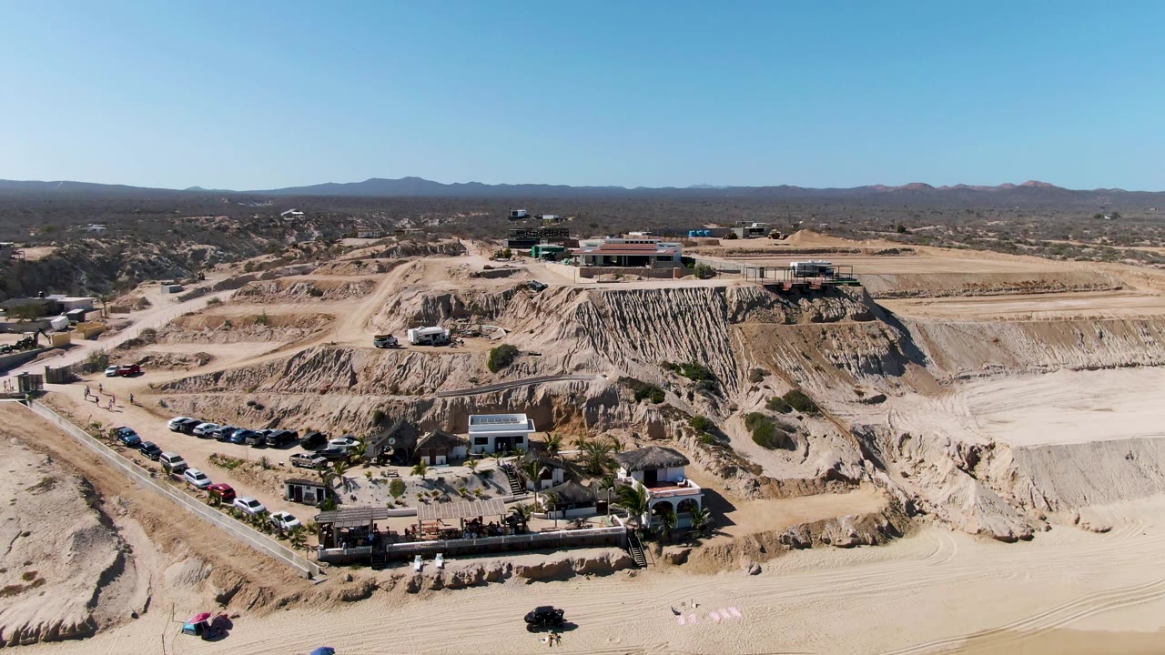 Second frame shows the La Fortuna quarry from above with the access road more centered, parked vehicles along the slope, buildings on the cut earth, and no visible people.