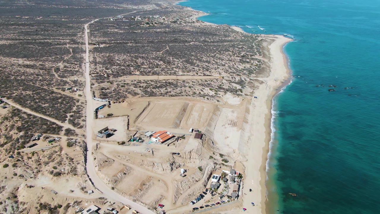 Aerial view of a coastal construction site beside turquoise ocean water.