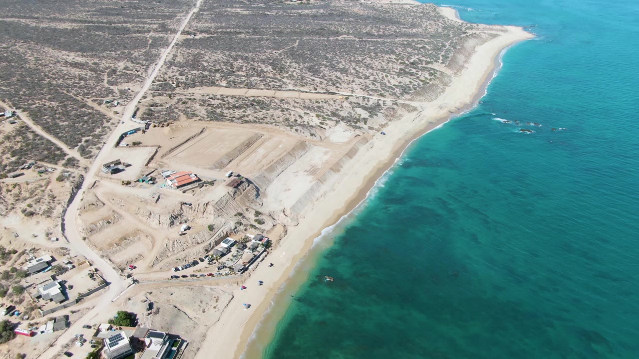 Aerial view of a coastal construction site beside turquoise water.