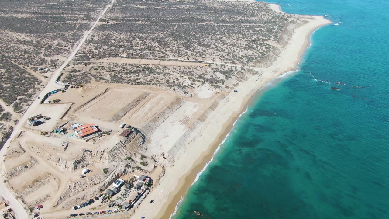 Aerial view of sandy beach, turquoise ocean, and coastal construction area