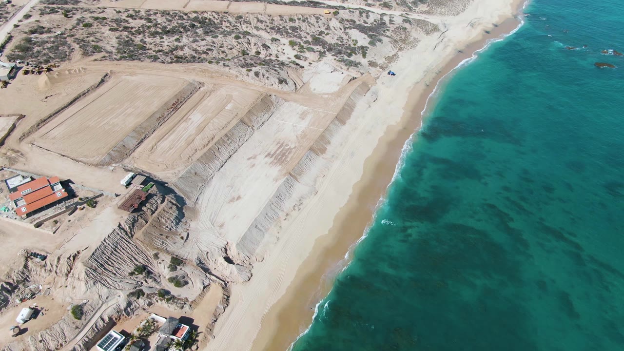 Aerial beach and coastal building area with the ocean occupying much of the frame.