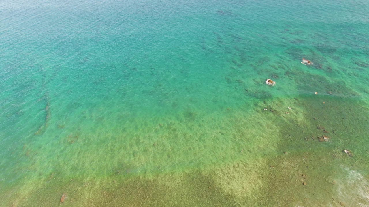 Clear shallow sea at La Fortuna, Baja California Sur, with rippled turquoise water, scattered darker submerged patches, and a pale green seabed, no visible people.