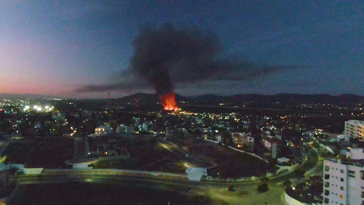 Wide dusk cityscape with distant fire and smoke
