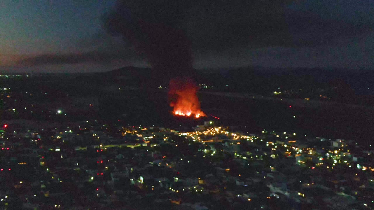 Night aerial city view with distant fire and black smoke