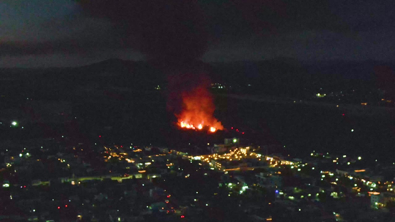 Distant night fire above city lights with smoke rising