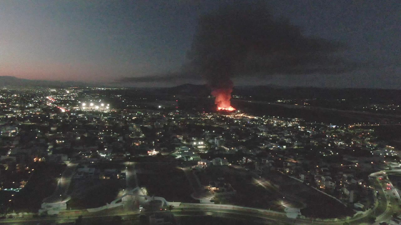 Dusk aerial city view with distant fire and smoke plume