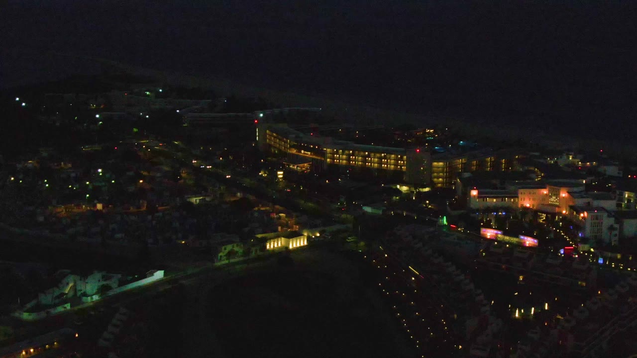 Night drone view of roads, lights, and coastal buildings