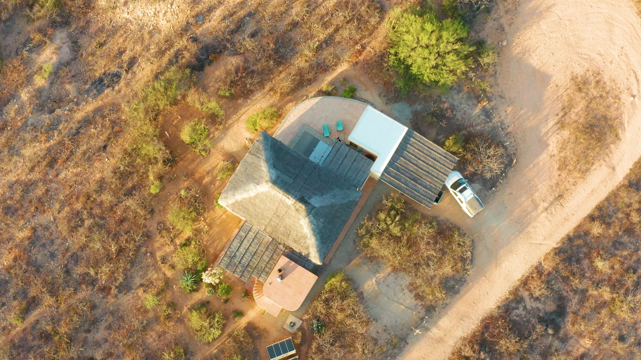 Aerial top-down view of a rural house with a white vehicle by the road.