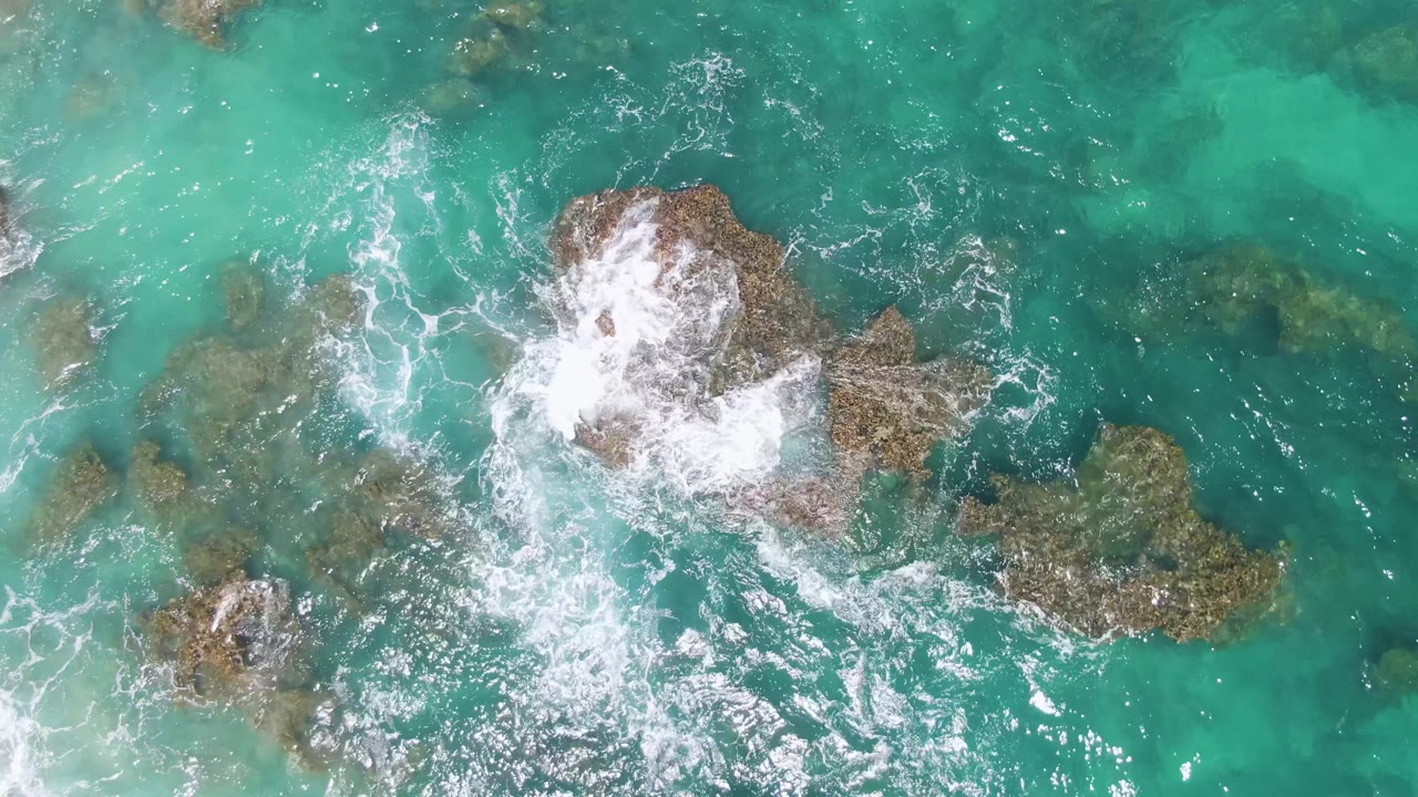 Overhead turquoise water breaking over rocky outcrops.