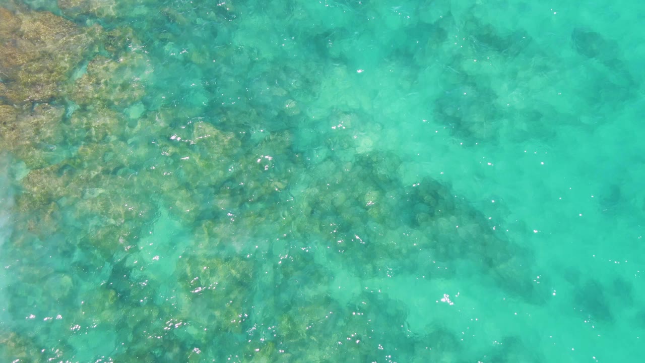 Overhead view of blue-green Buzzards Beach water with submerged rock shapes under light ripples and no visible people.