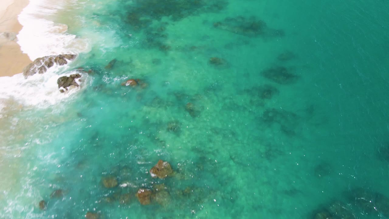 Rocky surf line at edge of wide turquoise shallows