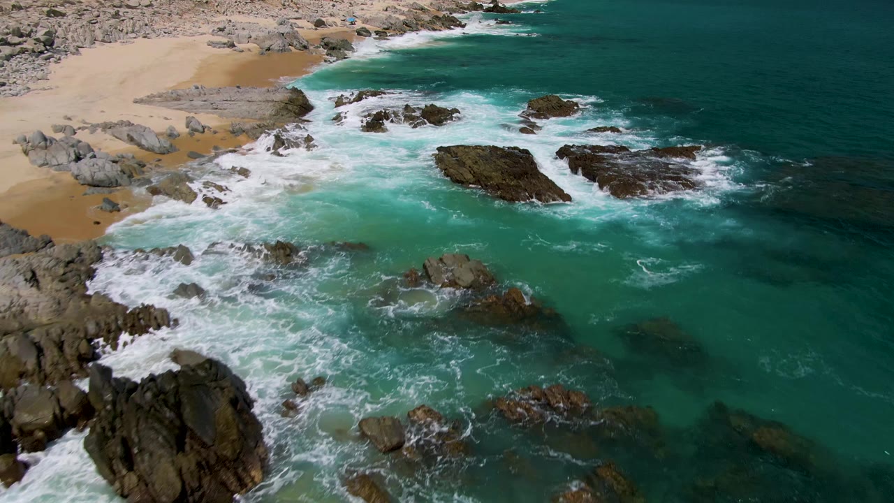 Rocky shoreline with waves washing into clear green-blue water