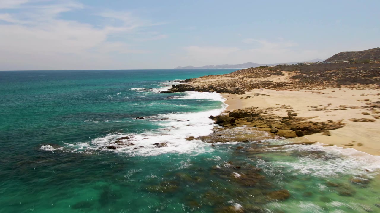 Turquoise ocean waves breaking along a rocky sandy coastline